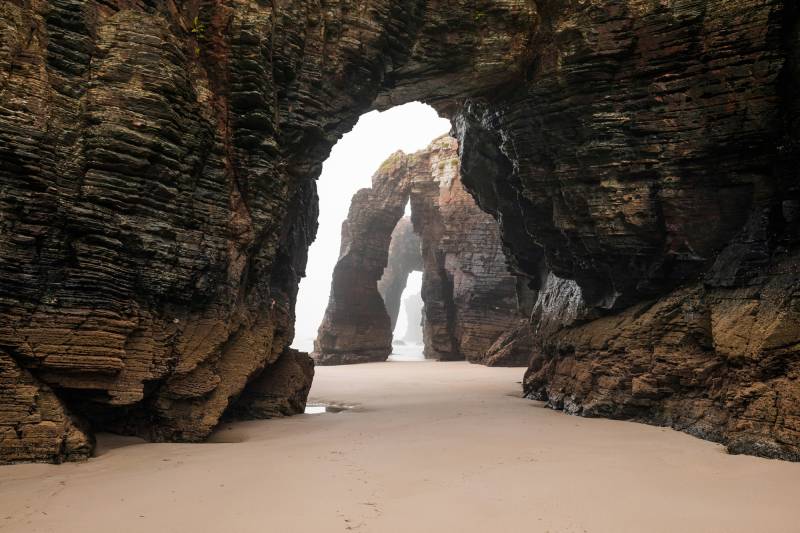 Papermoon Fototapete »GROTTE-FELSEN EBBE SPANIEN TUNNEL STRAND DUNEN MEER« von Papermoon